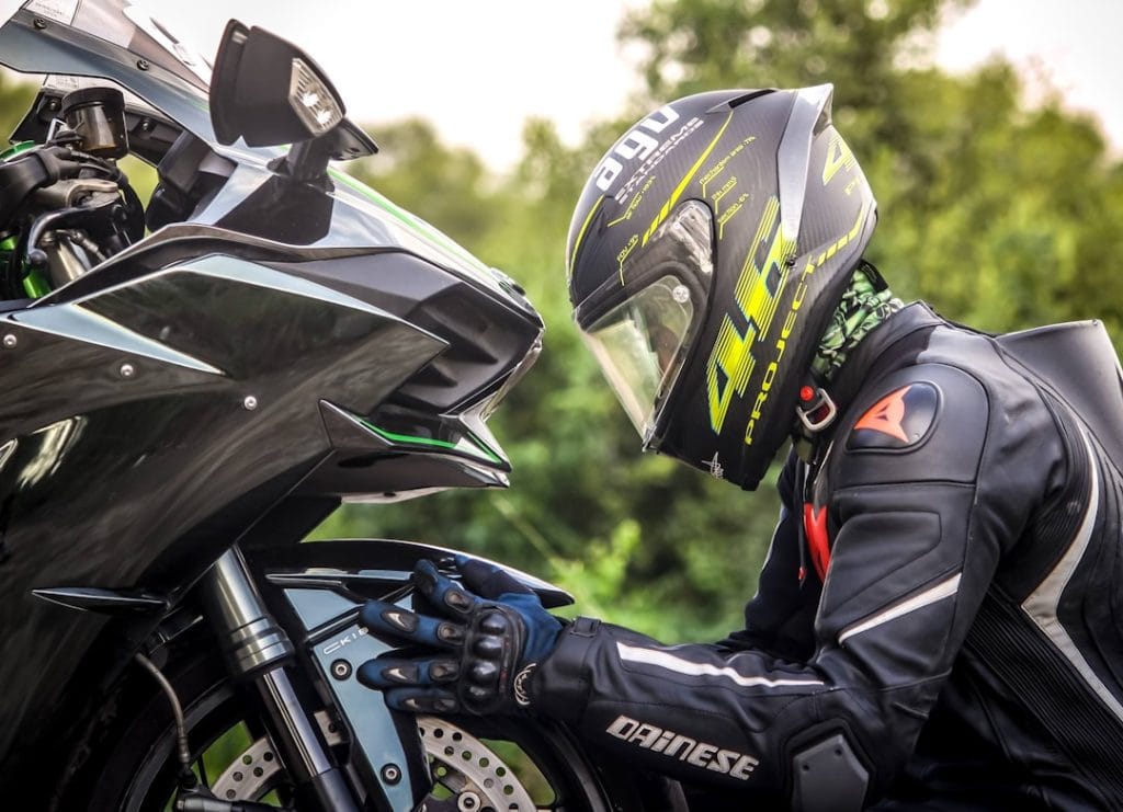 Rider wearing a helmet holding a motorcycle